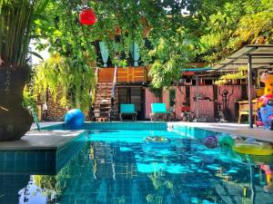 een zwembad in een achtertuin met bomen en een huis bij De Wiang Kum Kam in Chiang Mai