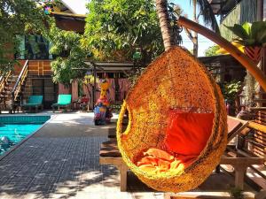a swing hanging from a tree next to a pool at De Wiang Kum Kam in Chiang Mai