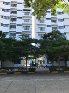 a large white building with trees in front of it at Sunshine Gypsy at Beach Villa Vibhavadi Pattaya in Na Jomtien