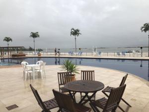 a patio with a table and chairs next to a pool at Lindo apto em Arraial do Cabo condomínio Golden Lake in Arraial do Cabo