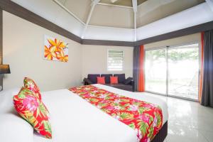 - une chambre avec un grand lit et une grande fenêtre dans l'établissement Hotel Koulnoue Village, à Hienghène
