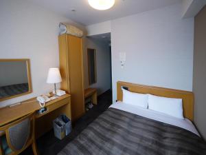 a hotel room with a bed and a desk and a television at Hotel Route-Inn Sapporo Shiroishi in Sapporo