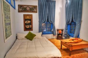 a bedroom with a bed with blue curtains and a table at Chikan West House in Tainan +33 photos