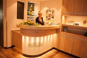 a woman standing behind a counter in acision at Landhotel Napoleon in Wipperfürth