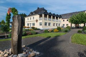 ein großes weißes Gebäude mit einer Steinstatue davor in der Unterkunft Ferienwohnung Römerweinhof in Neumagen-Dhron
