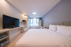a hotel room with a large bed and a flat screen tv at SureStay Plus Hotel by Best Western Asan in Asan