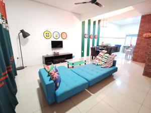 a living room with a blue couch with pillows at The Woodz Homestay - 2 Storey Landed House in Cameron Highlands