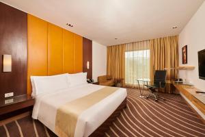 a hotel room with a large bed and a desk at Holiday Inn Mumbai International Airport, an IHG Hotel in Mumbai