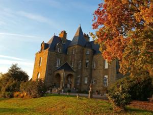 a large brick building with a tree in front of it at Château de Montbrault in Fleurigné