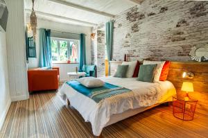 a bedroom with a bed and a brick wall at Domaine du Lieu des Brocs - Country Club in Brucourt