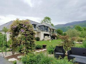 a house with two black chairs in a yard at Le balcon des cimes in Adast