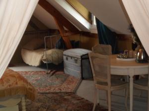 a attic room with a table and a bed at Les Chambres de Pontfol - Chambres d'hôtes - Guest house in Victot-Pontfol