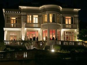 una gran casa blanca con gente de pie fuera por la noche en Villa Fani, en Thiers
