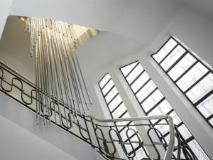 a staircase with a chandelier in a room with windows at Villa Fani in Thiers