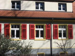 una fila di finestre con persiane rosse in un edificio di Haus am Apfelbaum a Bad Säckingen