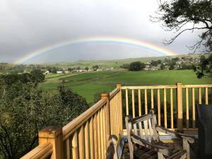 einen Regenbogen über einem Deck mit einer Bank vorne in der Unterkunft The Sett on The Wharfe in Threshfield