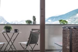 un tavolo e una sedia sul balcone con vista sulle montagne di Hotel Luise a Riva del Garda