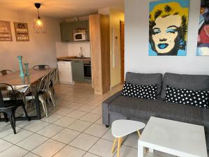 een woonkamer en een keuken met een bank en een tafel bij appartement au pied des pistes in La Chal