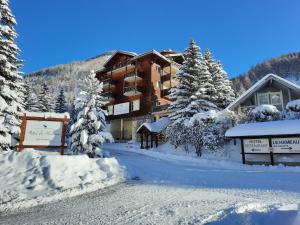 a lodge in the snow with snow covered trees at Hôtel du Hameau in La Foux