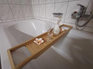 una vasca da bagno con vassoio in legno con un bicchiere di vino e fiori di Ferienwohnung Ela a Reutte