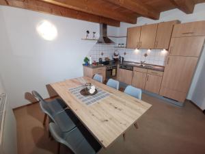uma cozinha com uma mesa de madeira e cadeiras azuis em Ferienwohnung Ela em Reutte