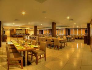 ein Esszimmer mit Tischen und Stühlen in einem Restaurant in der Unterkunft Hotel Le Ruchi The Prince in Mysore