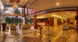 um lobby de um hotel com cadeiras e mesas em Hotel Le Ruchi The Prince em Mysore