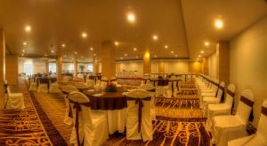 a banquet hall with white tables and white chairs at Hotel Le Ruchi The Prince in Mysore +16 photos