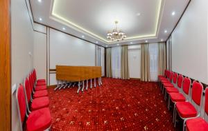 a conference room with red chairs and a chandelier at Отель МашБах in Cherepovets
