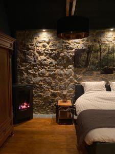 - une chambre avec un mur en pierre, un lit et une cheminée dans l'établissement La LAITERIE Ecaussinnes, à Les Croisettes