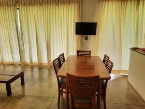 una mesa de madera y sillas en una habitación con cortinas en The View at Glenloch - Home Stay en Tawalantenna