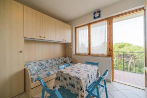een kamer met een tafel en stoelen en een raam bij Monolocali Le Lecce Pool & Tennis in Capoliveri