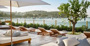 a patio area with chairs, tables and umbrellas at Nobu Hotel Ibiza Bay in Talamanca