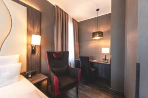 um quarto de hotel com uma cama, uma secretária e cadeiras em PLAZA Premium Parkhotel Norderstedt em Norderstedt