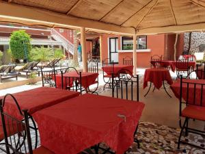 a restaurant with red tables and chairs under a umbrella at Hotel Grazia Maria in Saly Portudal