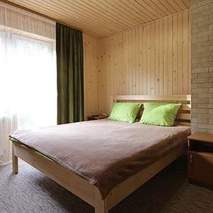 Un dormitorio con una cama con almohadas verdes y una ventana en Садиба Срібні Карпати en Yablunytsya