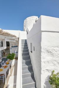a staircase leading up to a white building with white tables and chairs at The Windmill Kimolos in Kimolos