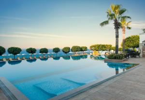 a swimming pool with chairs and a palm tree at Xanadu Island in Akyarlar