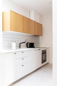 eine Küche mit weißen Geräten und Holzschränken in der Unterkunft Tinto Townhouse by Olala Homes in Sevilla