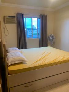 um quarto com uma cama, uma janela e uma ventoinha em Apartamento em itapema em Itapema