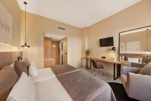 パルマ・デ・マヨルカにあるホテル アルムダイナのベッドとデスクが備わるホテルルームです。