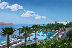 a resort with a pool and palm trees and chairs at Xanadu Island in Akyarlar