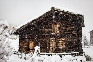 サースフェーにあるハウス ベル ヴューの吹雪の中の丸太小屋