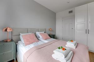 a bedroom with a pink and white bed with towels at Baltica Sky by TriApart in Gdańsk