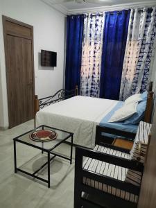 een slaapkamer met een bed en een tafel en een televisie bij Villa Soudan in Bobo-Dioulasso