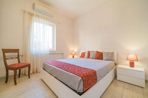 sypialnia z łóżkiem, krzesłem i oknem w obiekcie Suite Alarcon w mieście Porto Azzurro