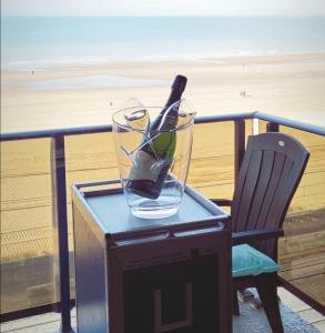 een glazen vaas op een tafel met een stoel en het strand bij Renovated studio direct Seaview in Oostende