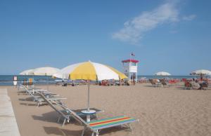 リミニにあるResidence Internazionaleの浜辺のビーチチェアとパラソル
