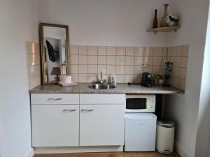een witte keuken met een wastafel en een magnetron bij Evy's place in Zandvoort