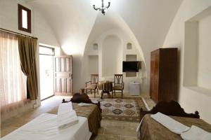 a bedroom with two beds and a table with a television at Urfaevi Butik Oteli in Sanlıurfa